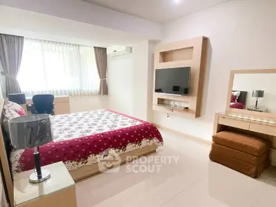 Spacious bedroom with modern decor, featuring a mounted TV and elegant furnishings.