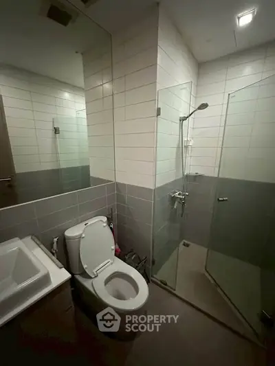 Modern bathroom with glass shower and sleek fixtures in contemporary apartment.