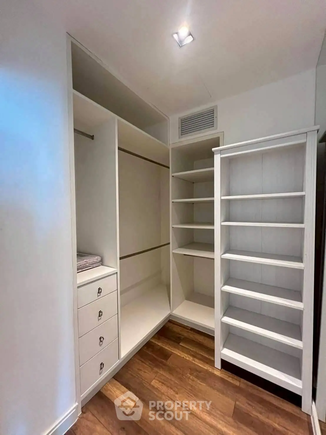 Spacious walk-in closet with wooden flooring and ample shelving