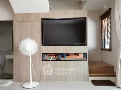 Modern living room with sleek TV setup and stylish fan, perfect for cozy entertainment.
