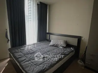 Cozy bedroom with dark curtains and modern bed frame, perfect for relaxation.