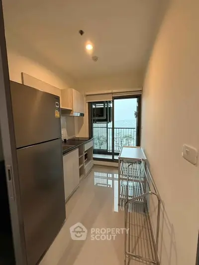 Modern kitchen with sleek appliances and balcony view in urban apartment