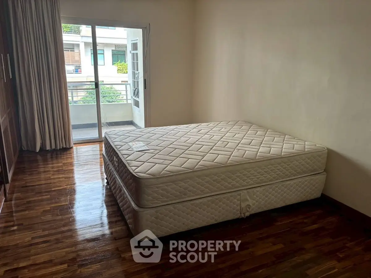Spacious bedroom with balcony access and polished wooden floors