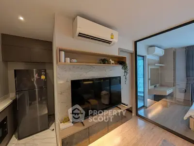Modern apartment interior with open layout, featuring sleek kitchen and cozy living area with large TV.