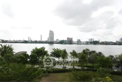 Stunning riverfront view with lush greenery and city skyline, perfect for serene living.