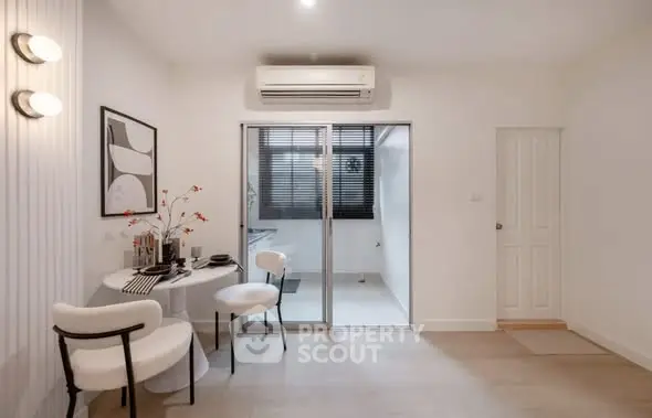 Modern dining area with stylish decor and sliding glass doors leading to a bright room.
