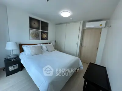 Modern bedroom with stylish decor and ample natural light, featuring a comfortable bed and sleek furnishings.