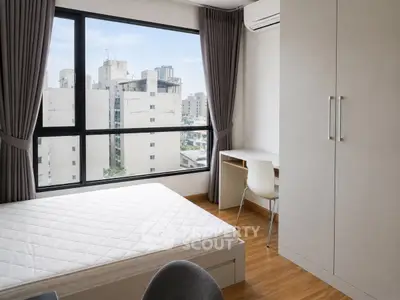 Modern bedroom with large window and city view, featuring a minimalist design and ample natural light.
