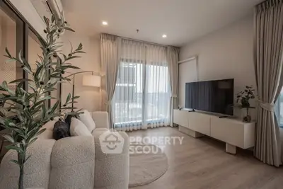 Modern living room with large windows, cozy sofa, and sleek TV setup.