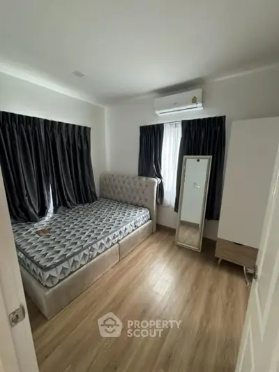 Cozy bedroom with modern decor and natural light, featuring a stylish bed and sleek flooring.