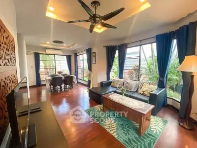 Spacious living room with elegant decor and large windows offering garden views.