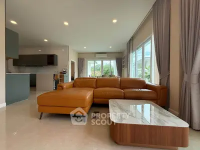 Spacious modern living room with leather sofa and marble coffee table, open to a stylish kitchen.