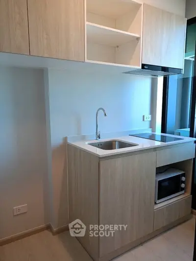Modern compact kitchen with sleek cabinetry and built-in appliances in a stylish apartment.