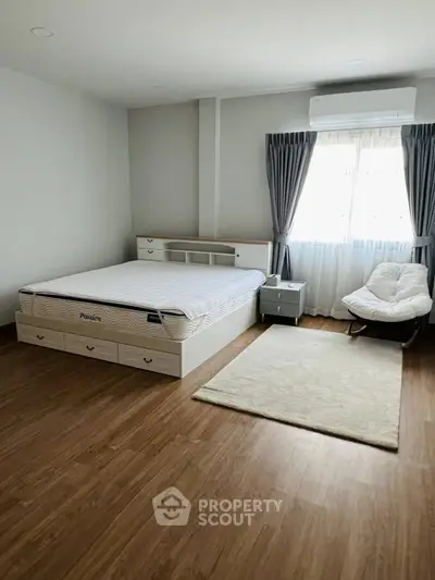 Spacious bedroom with wooden flooring and modern furniture