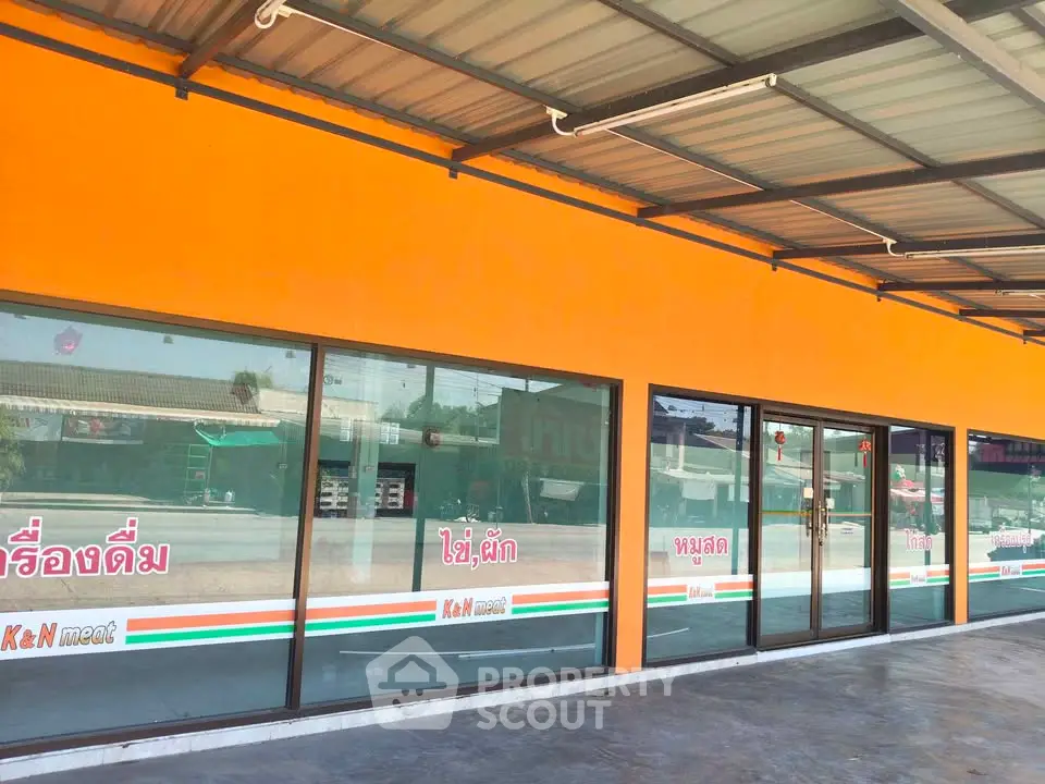 Vibrant commercial property with large glass windows and orange facade, ideal for retail business.