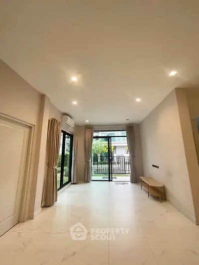 Spacious modern living room with large windows and garden view.