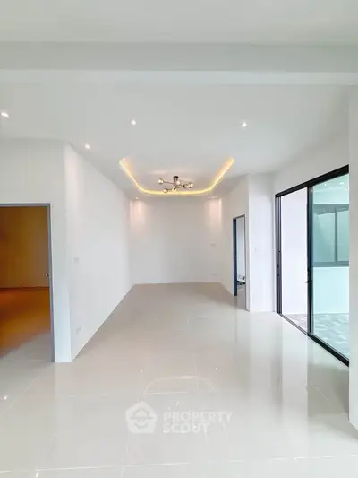 Spacious modern living room with sleek tile flooring and large sliding glass doors.