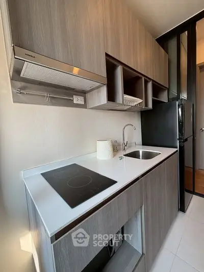 Modern kitchen with sleek cabinetry and electric cooktop in stylish apartment