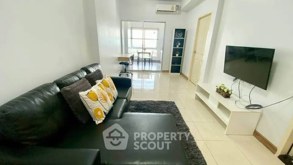 Spacious living room with modern decor and wall-mounted TV in a bright apartment.
