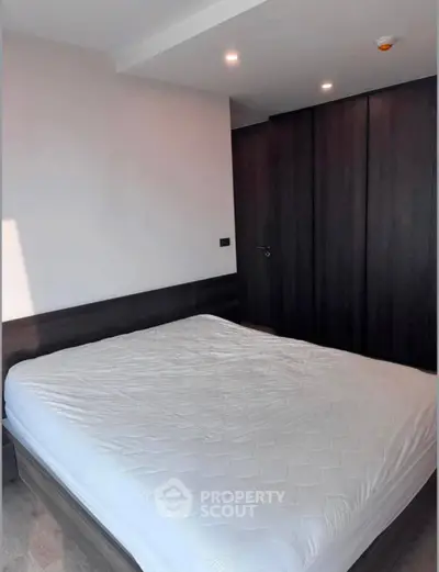 Modern bedroom with sleek dark wood wardrobe and cozy bed in minimalist design.