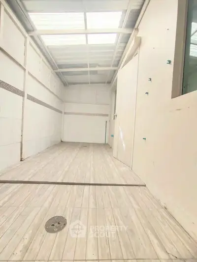 Spacious indoor area with high ceiling and wooden flooring, ideal for creative renovation.