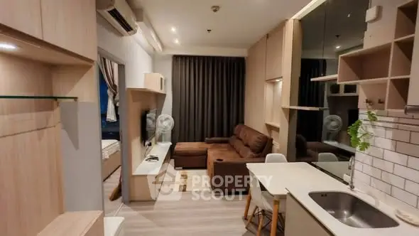 Modern living room with open kitchen, featuring sleek design and cozy seating area.