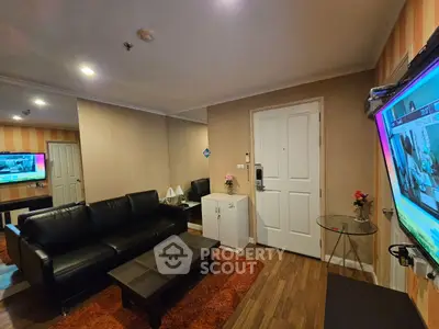 Modern living room with sleek black sofa and wall-mounted TV in cozy apartment.