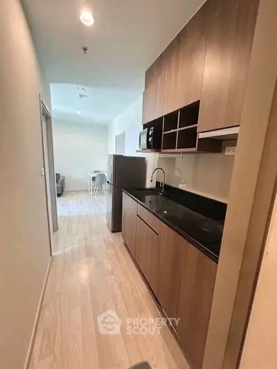 Modern kitchen with sleek wooden cabinets and black countertop in a cozy apartment.