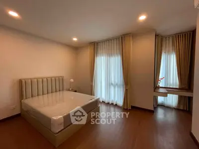 Spacious bedroom with elegant curtains and modern furnishings in a well-lit apartment.