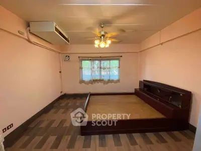 Spacious bedroom with built-in bed frame and ceiling fan, featuring large window for natural light.