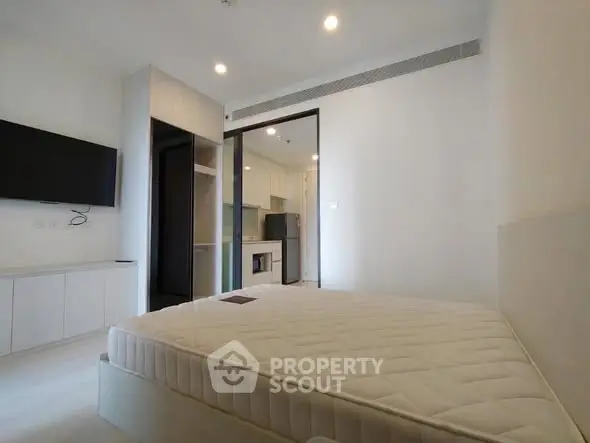 Modern bedroom with minimalist design and open kitchen view in a stylish apartment.