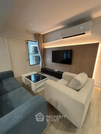 Modern living room with stylish furniture and wall-mounted TV, featuring sleek air conditioning unit.