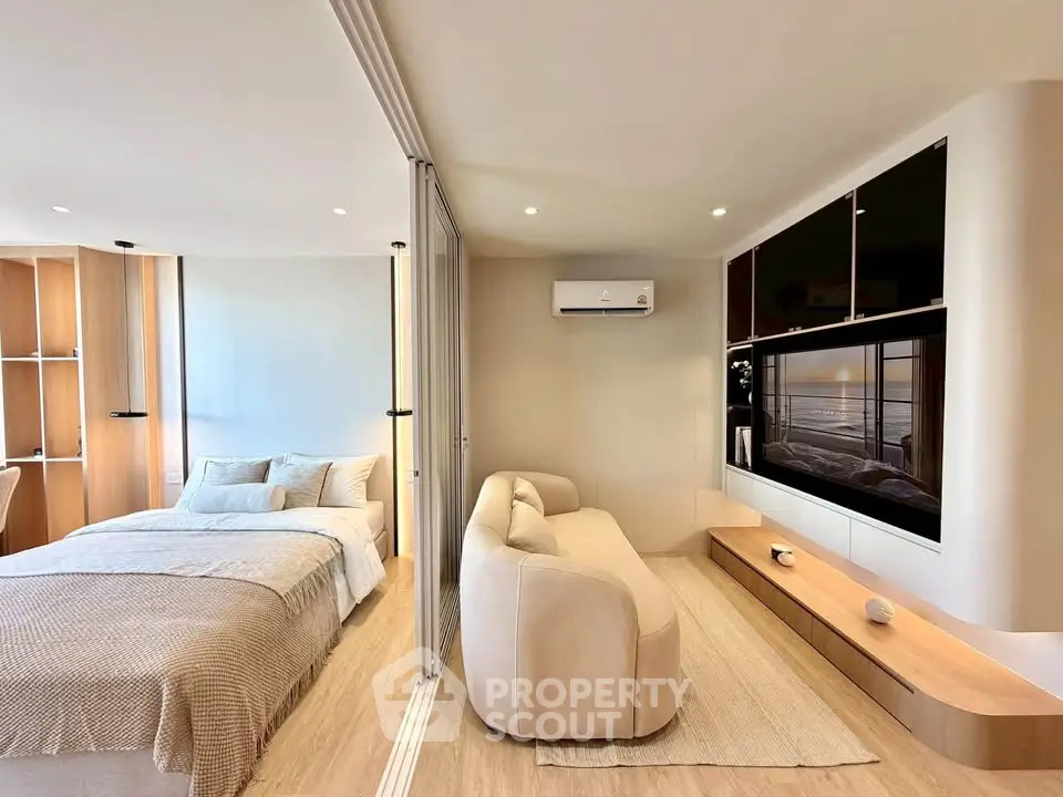 Modern studio apartment with open layout, featuring cozy bed and stylish living area with sleek TV setup.