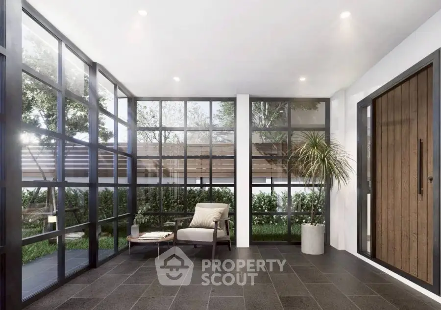 Modern sunroom with large windows and stylish decor, offering a serene garden view.