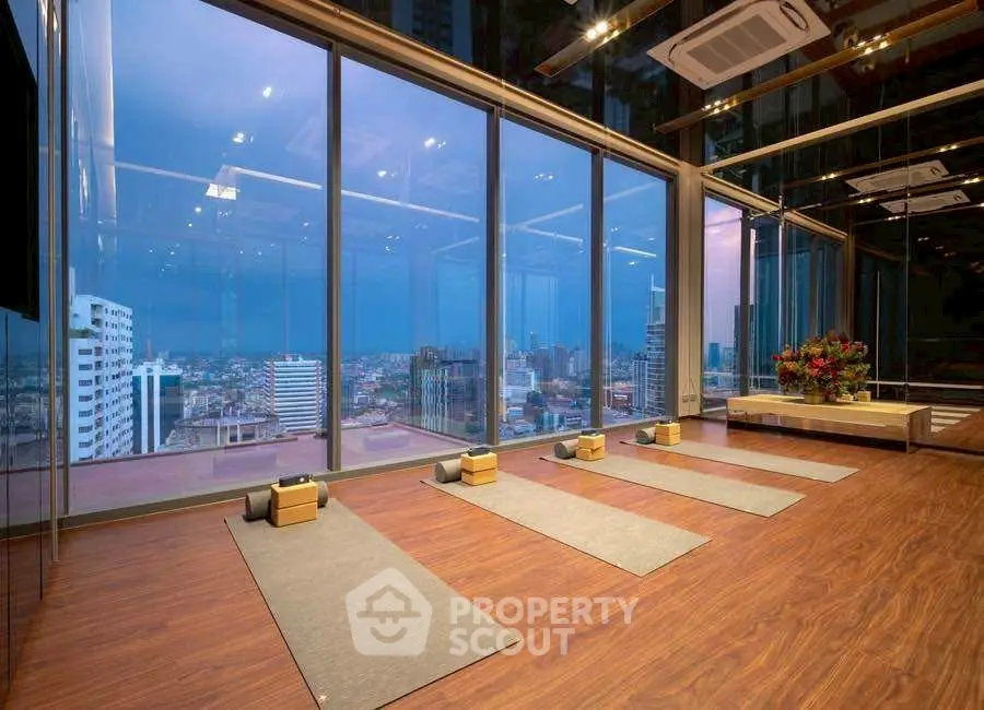 Luxurious yoga studio with panoramic city views and elegant wooden flooring.