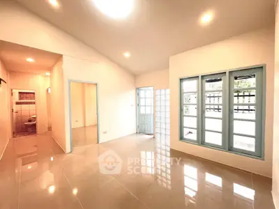 Spacious living room with glossy tile flooring and large windows for natural light.