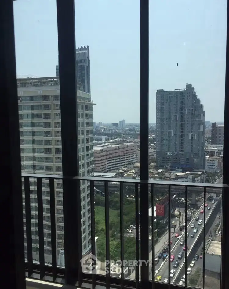 Stunning urban view from high-rise balcony overlooking city skyline and bustling streets.