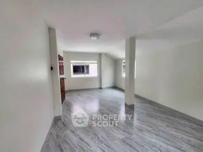 Spacious empty room with modern flooring and ample natural light.
