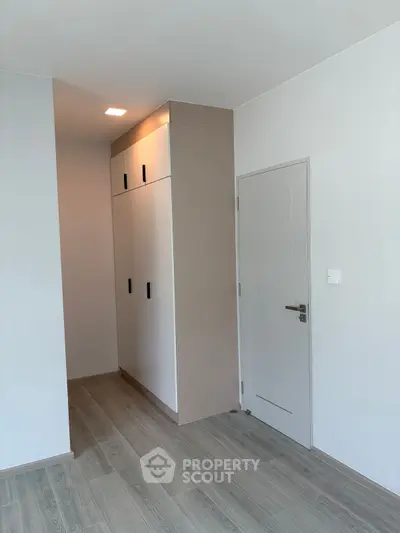 Modern minimalist bedroom with built-in wardrobe and sleek wooden flooring.