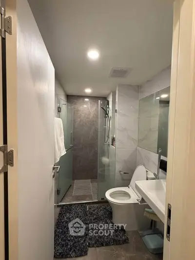 Modern bathroom with glass shower and sleek fixtures in a contemporary apartment.