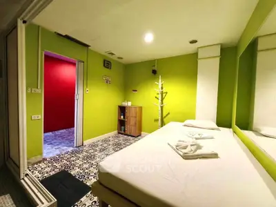Vibrant bedroom with green walls and modern decor, featuring a unique floor pattern and cozy ambiance.