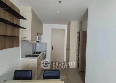 Modern kitchen with sleek cabinetry and dining area in a contemporary apartment.
