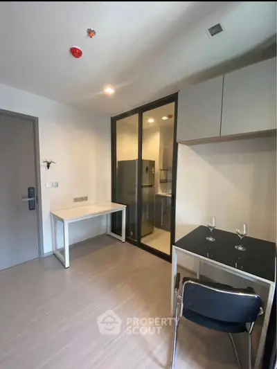 Modern kitchen with sleek design and glass partition, featuring a compact dining area and stylish cabinetry.