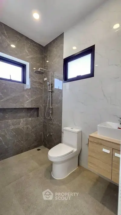Modern bathroom with sleek design, featuring a shower and stylish vanity.