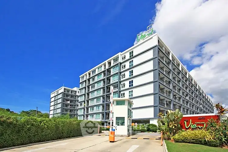Modern condominium building with lush greenery and clear blue sky, offering a serene residential environment.