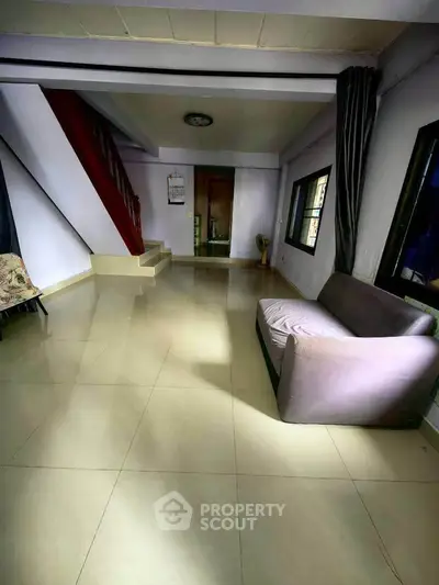 Spacious living room with modern staircase and cozy sofa, perfect for relaxation and entertaining guests.