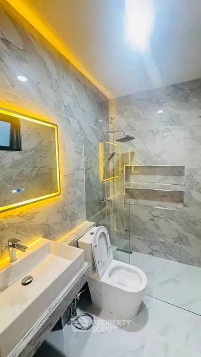 Luxurious modern bathroom with marble tiles and LED mirror lighting