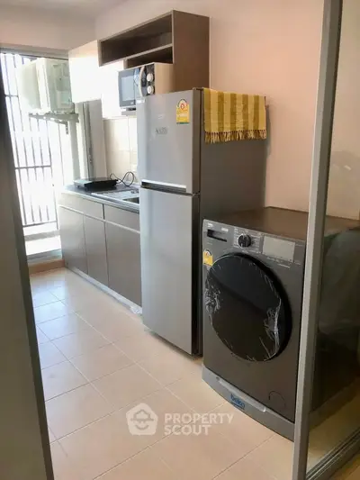 Modern kitchen with appliances including fridge and washing machine in a compact layout.