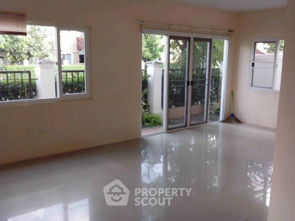 Spacious living room with large windows and garden view, perfect for natural light lovers.