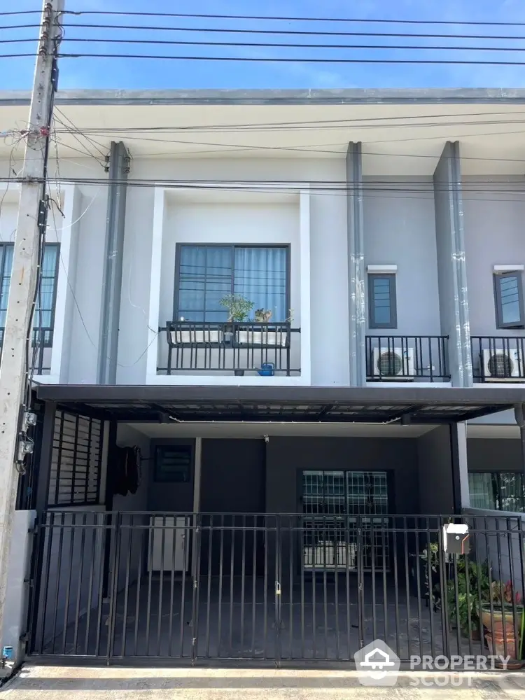 Modern townhouse exterior with gated entrance and balcony